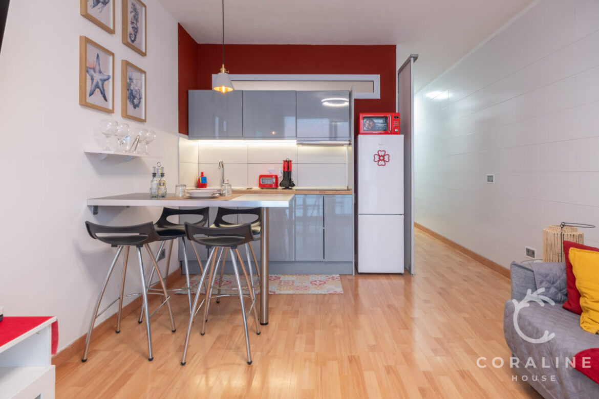 Cocina abierta con barra de desayuno y pared roja