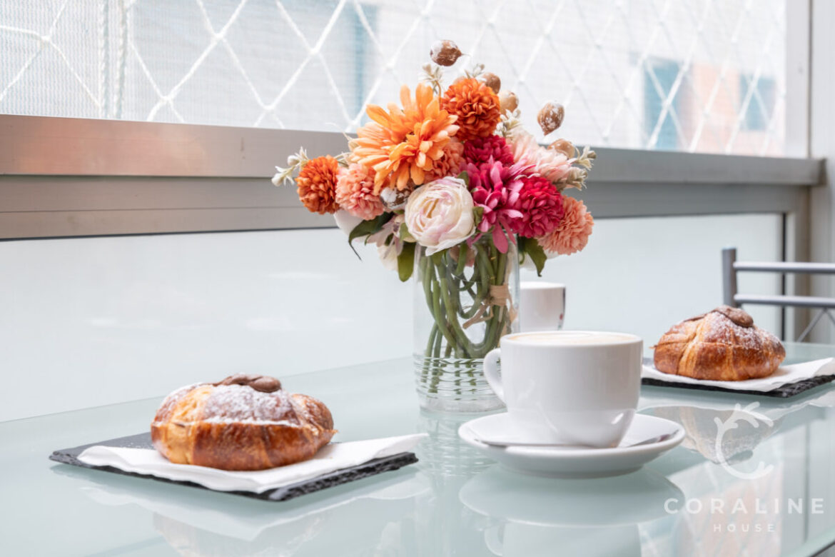 Café, bollería y flores sobre la mesa del balcón