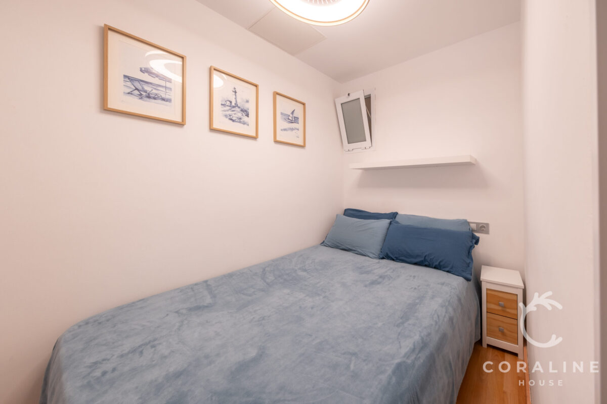 Dormitorio con cama de matrimonio y láminas marinas