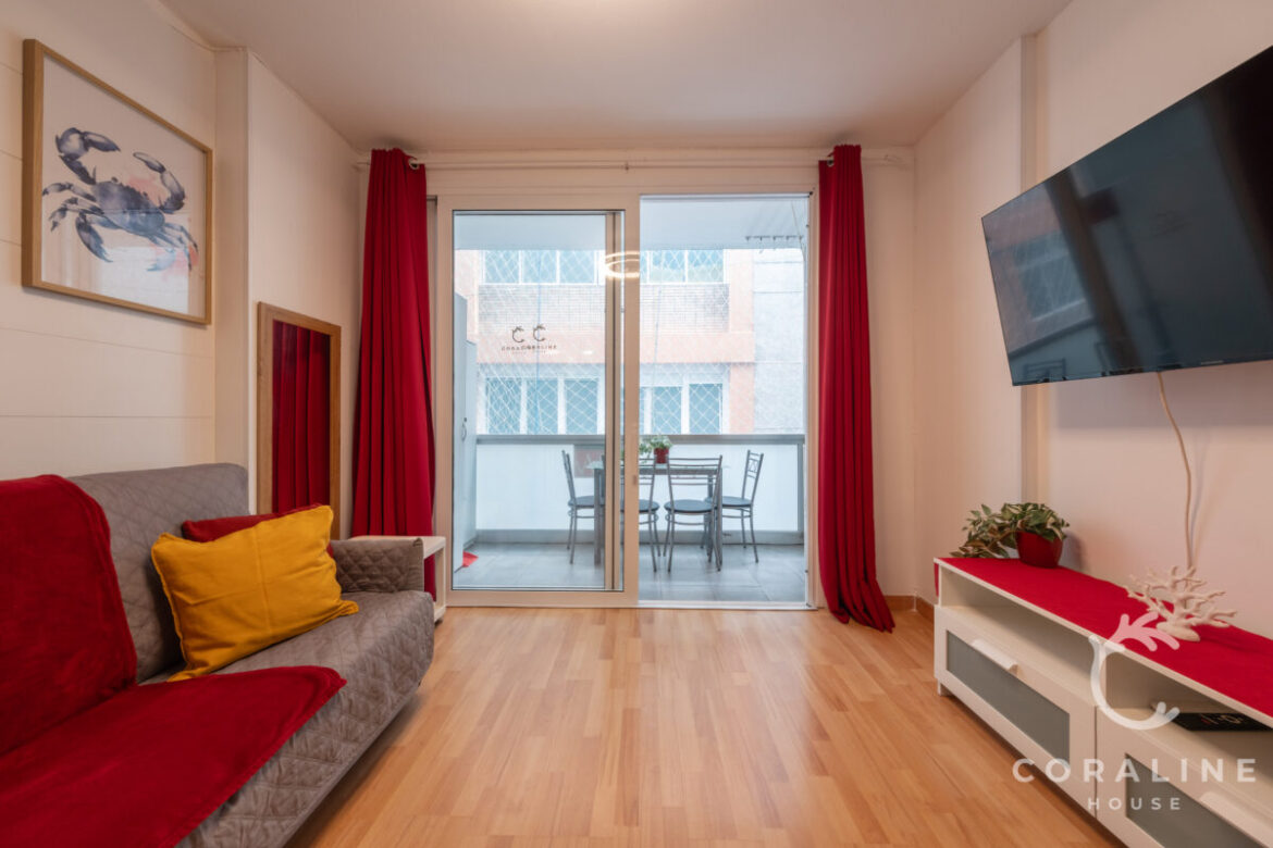 Salón con sofá, televisión y salida al balcón